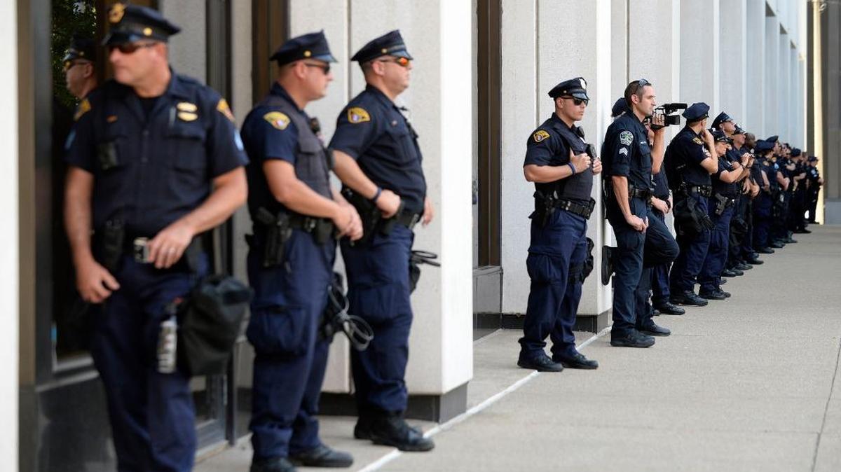 Police officers stand still as Anti-Trump organizations and Black Lives Matter protesters walk through downtown Cleveland on the first day of the Republican National Convention on Monday, July 18, 2016.