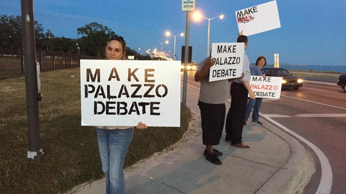 Protesters outside Tuesday’s Salute to the Military gala at the Coast Convention Center carry signs seeking to have U.S. Rep. Steven Palazzo, R-4, participate in a debate planned at the University of Southern Mississippi. Palazzo was instead attending the gala.
