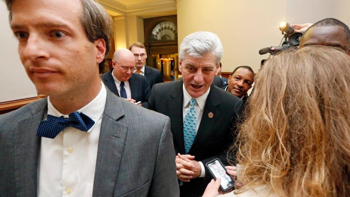 Republican Gov. Phil Bryant, center, walks behind his spokesman, Clay Chandler, left, as reporters ask him if he will sign a bill that would let government employees and private businesses cite religious beliefs to deny services to same-sex couples who want to marry, following a news conference on a youth jobs program at the Capitol in Jackson, Miss., Friday, April 1, 2016.