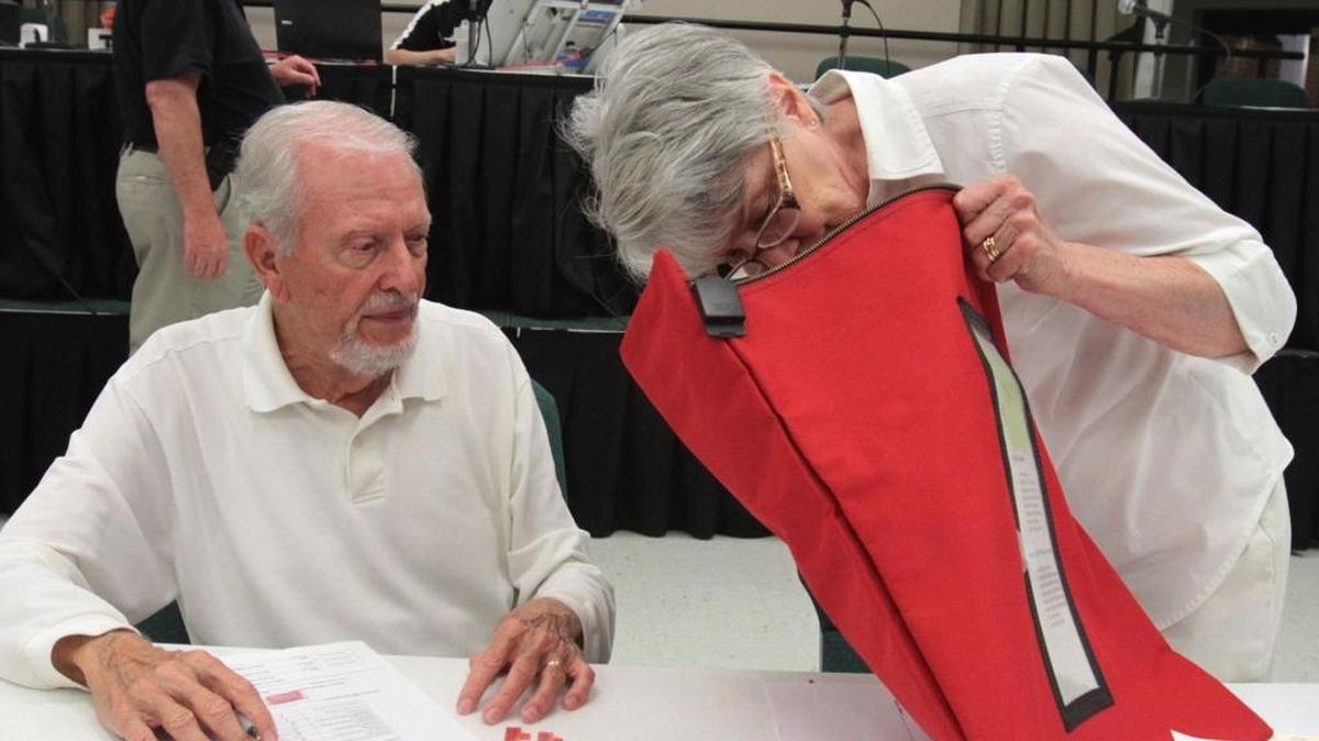 Election commissioners Judy and Frank Gaupp check a bag for absentee ballots at Diamondhead City Hall in 2013.