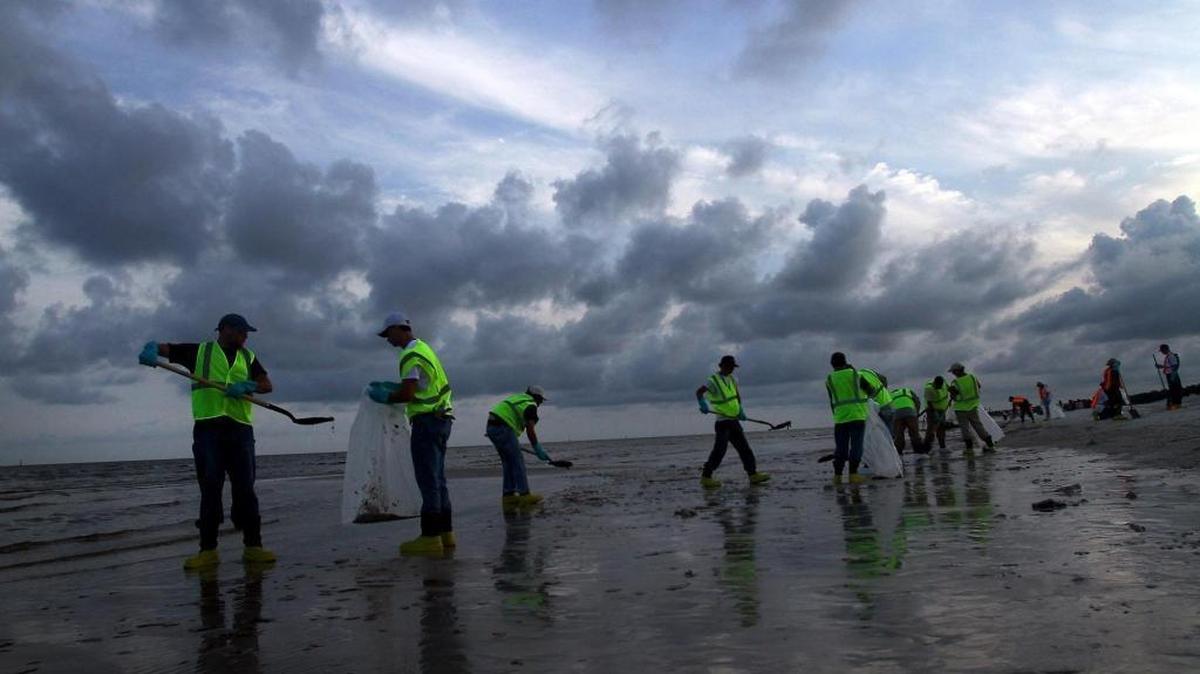 Cleanup crews work to remove tar balls and patties from the Deepwater Horizon oil spill that washed ashore in Long Beach on July 7, 2010.