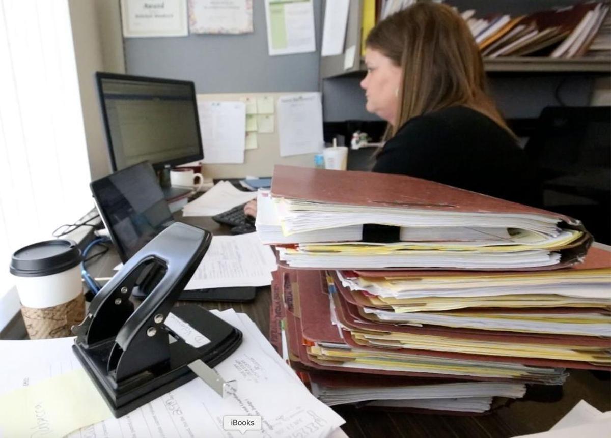 With a stack of case files on her desk, Mississippi Department of Human Services caseworker Rebekah Woodcock works in her office in Kiln on Thursday, July 7, 2016.
