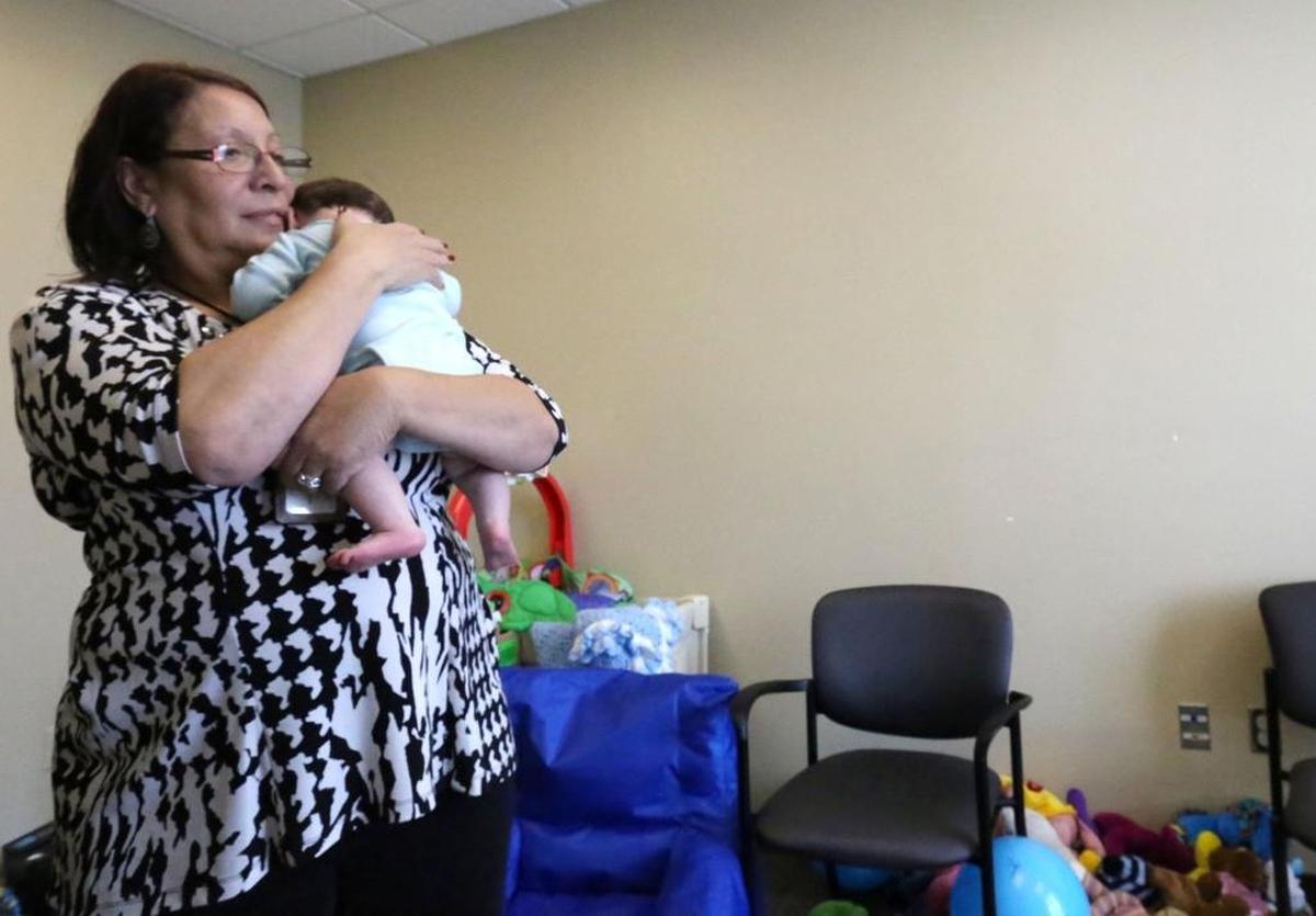 Hancock County Department of Human Services case aide Darlene Bradley holds a baby at the DHS office in Kiln while their parents attend Youth Court in March 2016. Case aides assist caseworkers with transportation, supervision of family visits and other logistical matters.