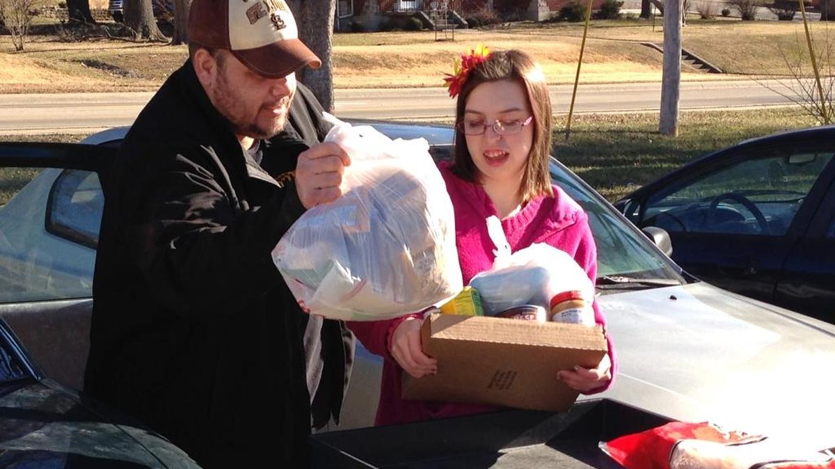 Joe Heflin, left, of Jefferson City, Missouri, loads free groceries into the backseat of his car with the help from a volunteer at the Samaritan Center food pantry in 2016. Heflin, 33, also receives federally funded food stamp benefits. Under a new Mississippi law that is being considered in other states, recipients would face tougher and more frequent eligibility checks.