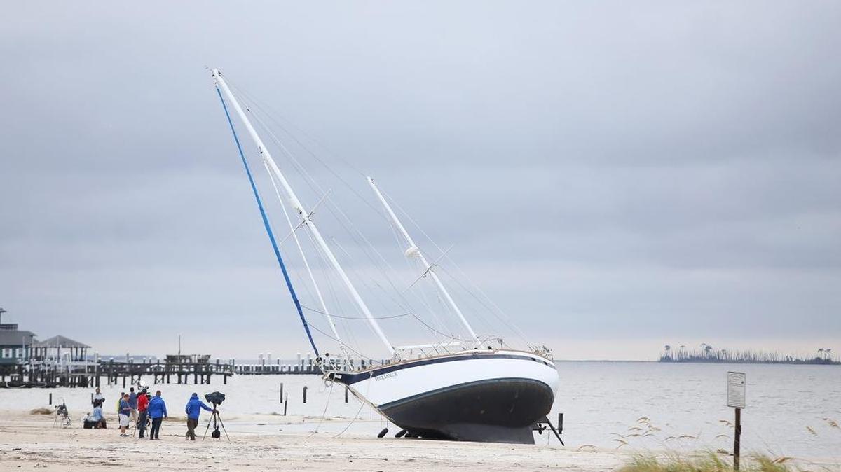Television crews on Sunday surround a boat that washed ashore on the beach in Biloxi sometime during Hurricane Nate.
