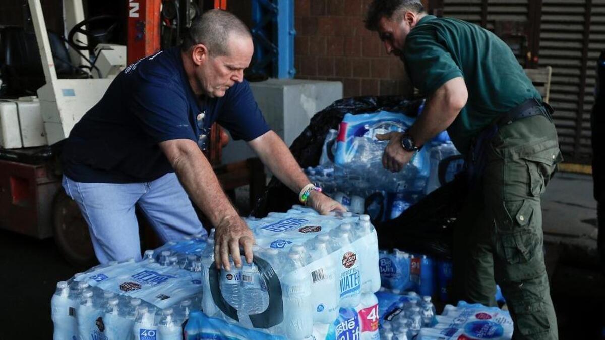 In this Wednesday, Sept. 27, 2017, photo, Roberto Clemente State Park employees re-stack cases of bottled water on a pallet after they were donated for the Empire State Relief and Recovery Effort for Puerto Rico, in New York.