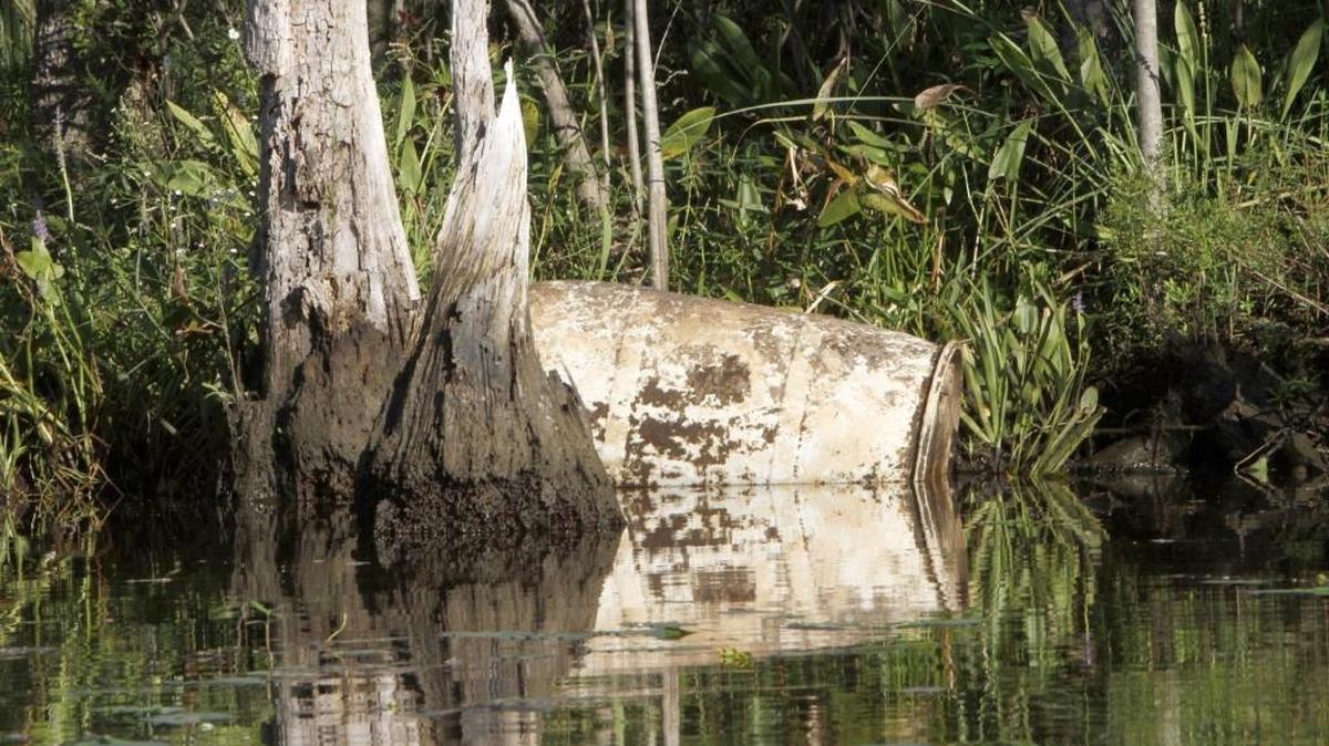 Barrels rest on the shoreline of the Pascagoula River.