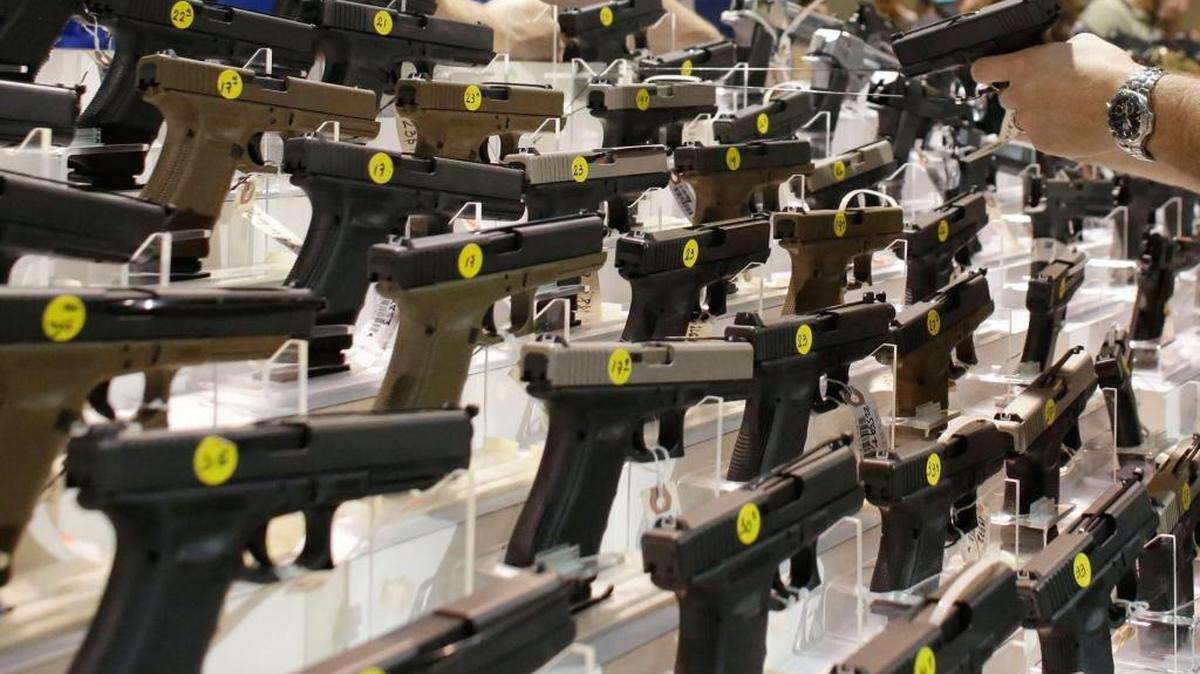 A customer looks at a pistol at a vendor's display at a gun show held by Florida Gun Shows in Miami in January 2016.