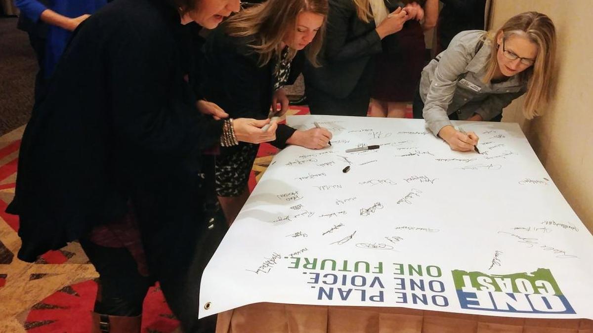 People from the audience at the Mississippi Gulf Coast Chamber of Commerce Pre-Legislative Briefing sign a banner that will head to Jackson for the annual Legislative Reception.