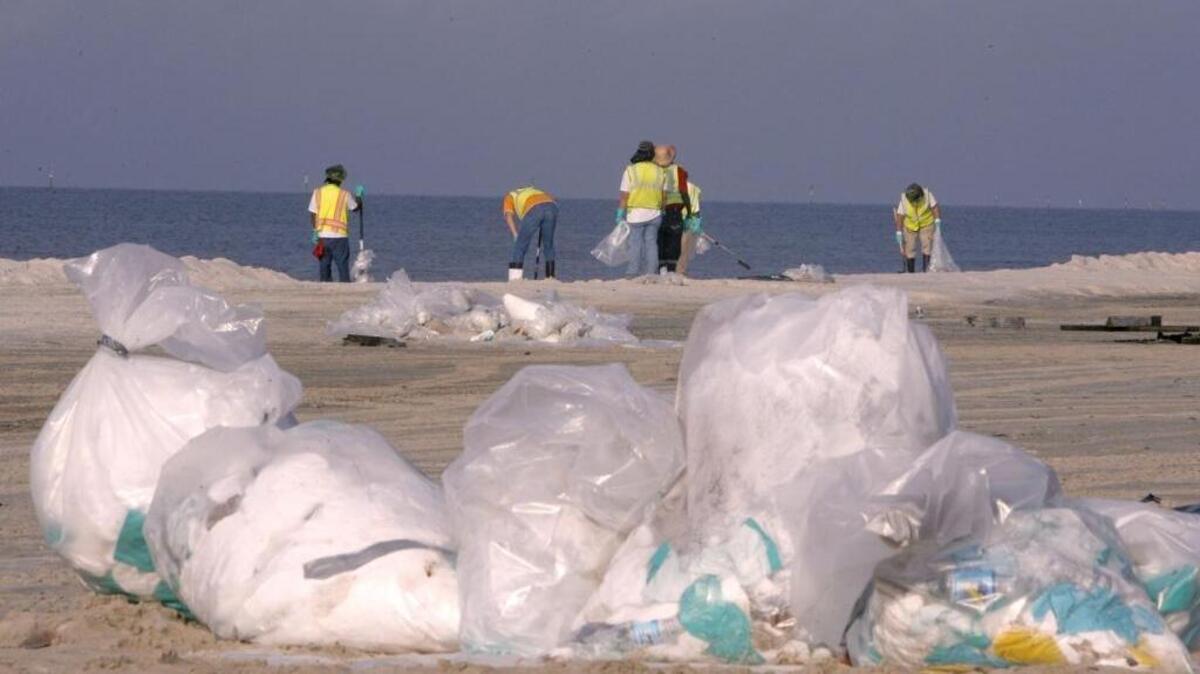 Crews clean up tar balls from the beach during the BP oil Spill.