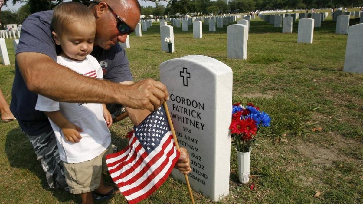 Shane Whitney helps his son Corbin place a U.S. flag at the grave of Gordon Patrick Whitney at the Biloxi National Cemetery in 2016. Gordon Whitney served in the U.S. Army in Vietnam. He was the father of Shane and grandfather of Corbin.
