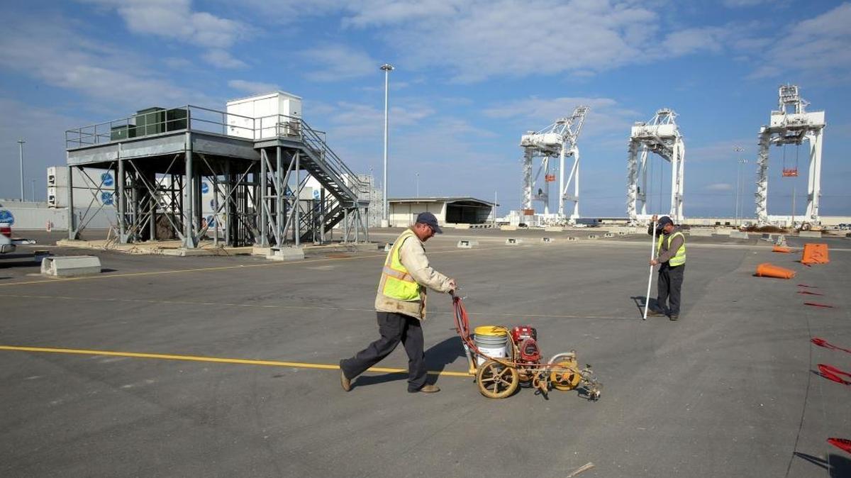 David Palmer and Michael Parker paint parking space stripes at the state Port of Gulfport recently.