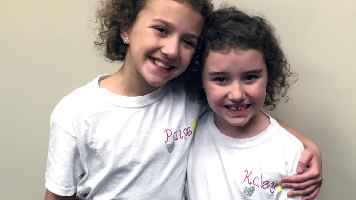 Paige and Kaley Wilson used money from their lemonade stand to buy mugs for state troopers.
