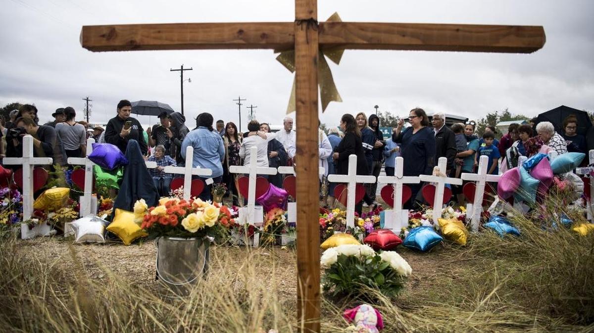 Dozens of people stand in the rain to pray and sing at the memorial crosses near the First Baptist Church of Sutherland Springs, Texas, one week after 26 people were killed there Nov. 5.