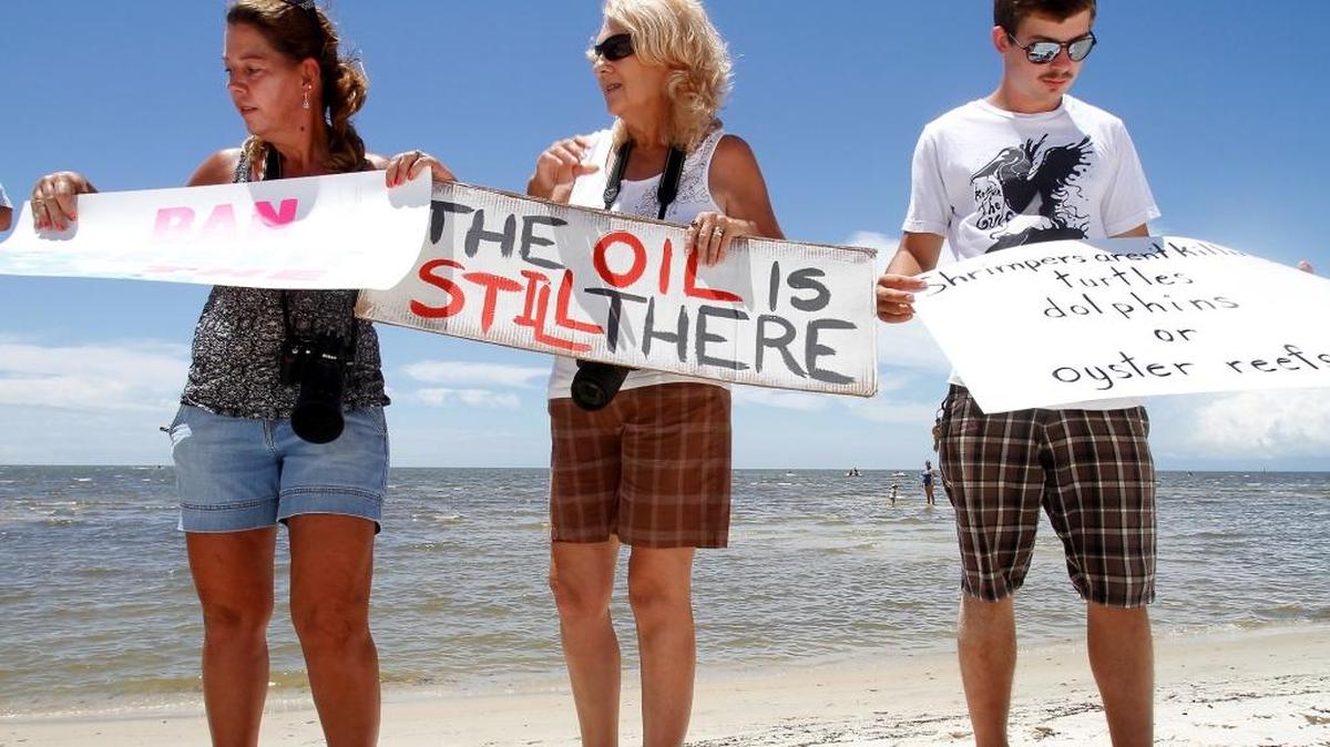 Laurel Lockamy of Gulfport, left, Shirley Tillman of Pass Christian, center, and Gilbert Ramseur of Ocean Springs take their signs while participating in the second annual Hands Across the Sand on the beach in Biloxi on Saturday, June 25 2011.