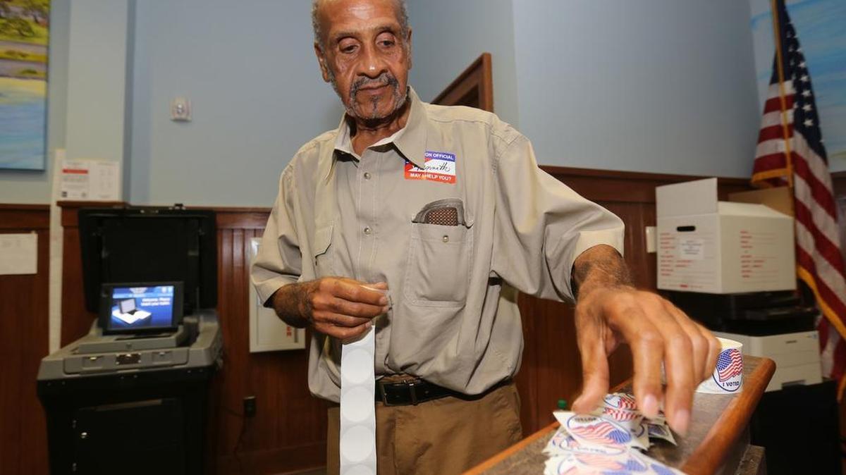 Kenneth Welch stacks up ‘I Voted’ stickers at the Pass Christian Municipal Courtroom for voters on June 5, 2018.