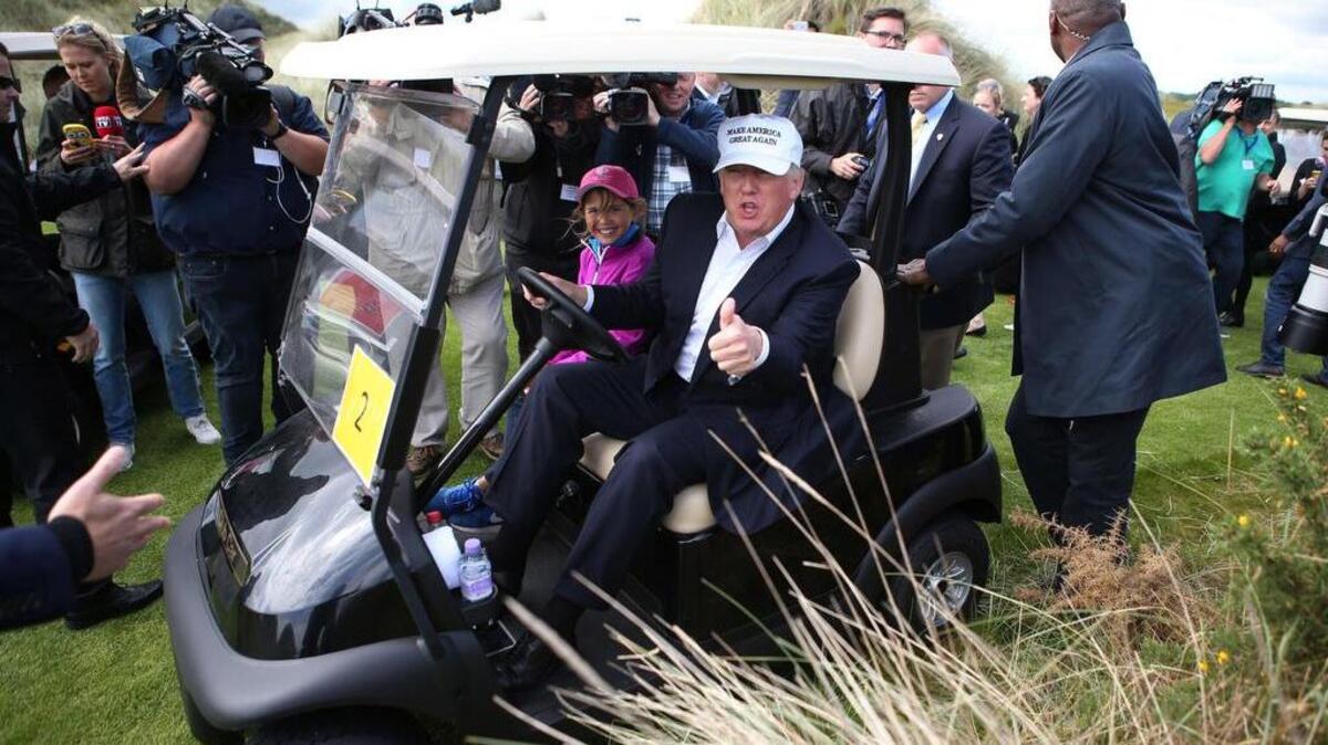 US presidential candidate Donald Trump chats with the watching media aboard a golf cart with granddaughter Kai after he arrived at the Trump International Golf Links at Balmedie, near Aberdeen, Scotland, Saturday June 25, 2016.