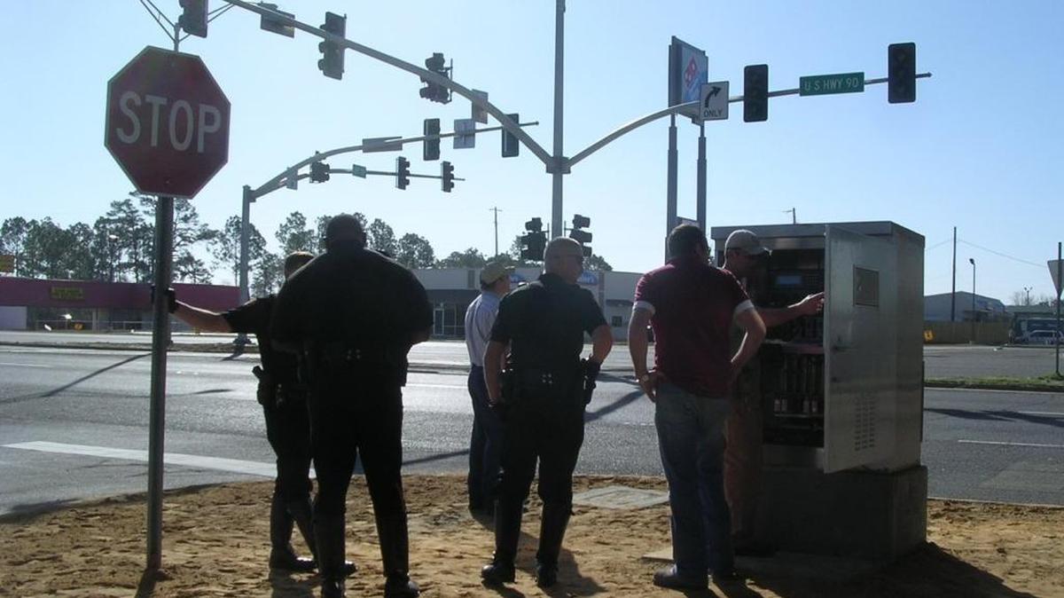 Police Lt. Matt Chapman (center) and other Pascagoula officers monitor traffic flow and operation of the new traffic light at 14th Street and U.S. 90 after the signal was turned on.