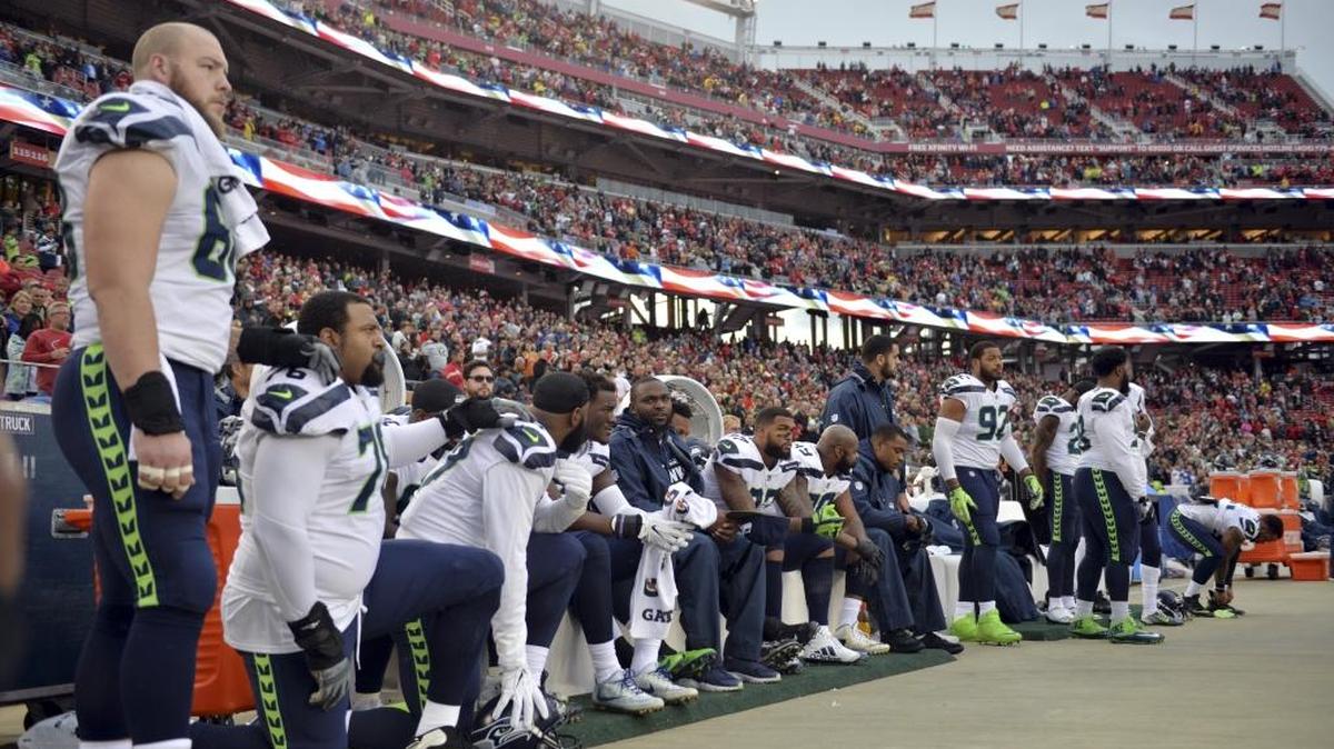 In this Nov. 26, 2017, file photo, Seattle Seahawks players sit and kneel during the playing of the national anthem before an NFL football game against the San Francisco 49ers, in Santa Clara, Calif. Players have been kneeling to protest racism and police brutality, particularly toward people of color.