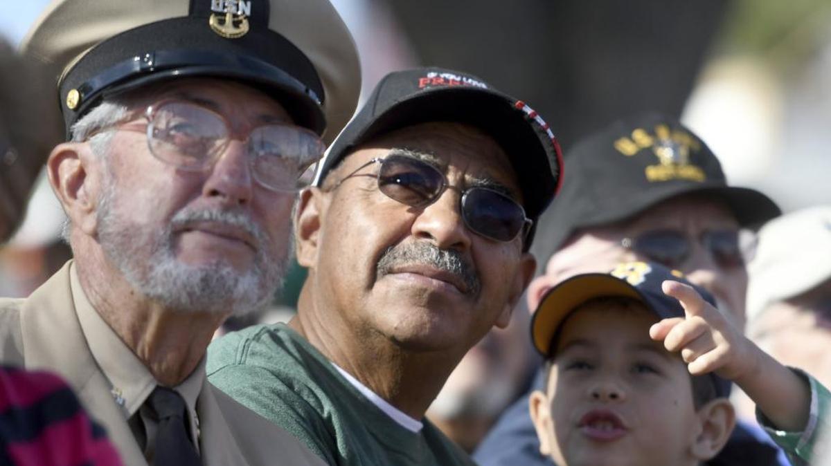 Richard E Satchell, left, Alan Ricard and his grandson James Ricard watch a video presentation during a Victorville, Calif., Veterans Day ceremony on Saturday, Nov. 11, 2017.