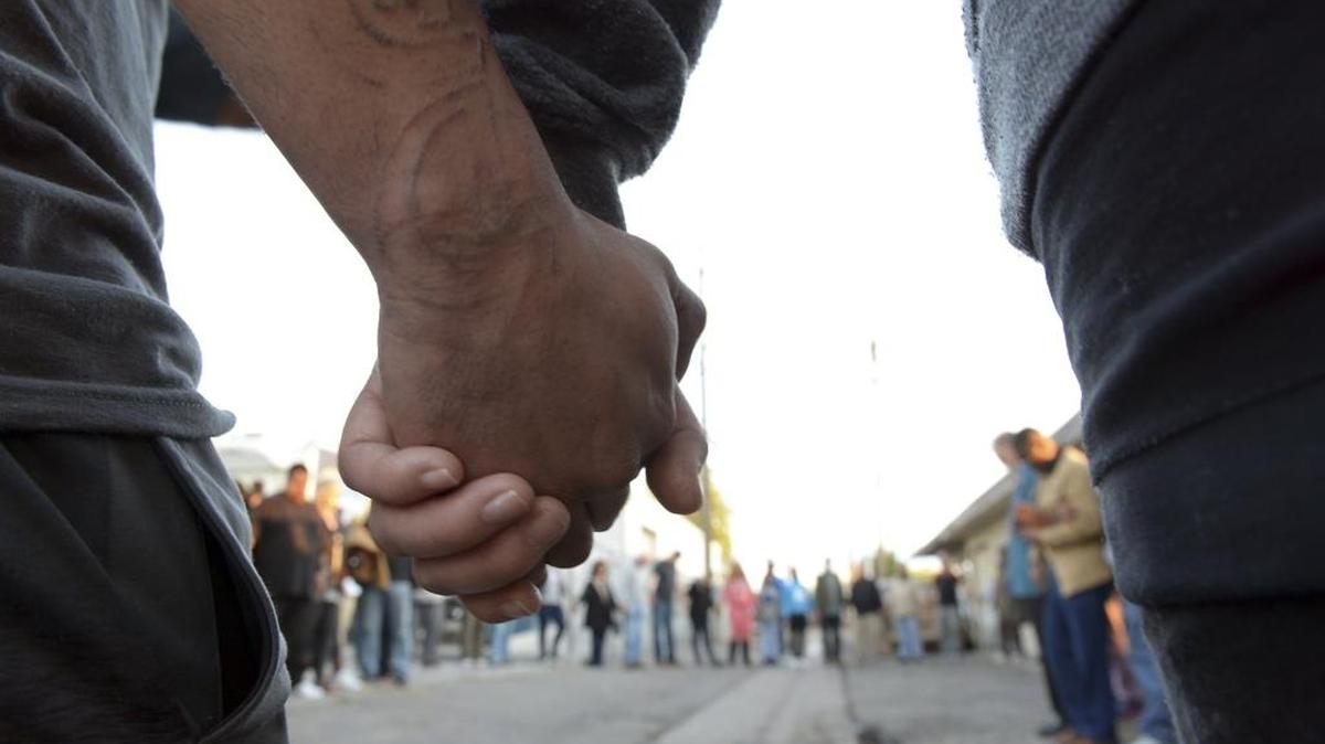 Community members and faith leaders from On Ramp Covenant Church hold hands during a prayer and vigil in the alley behind the Catholic Charities' Fresno Family Resource Center to honor the three shooting victims that were killed by a gun man on Tuesday morning, April 18, 2017, in Fresno, Calif.
