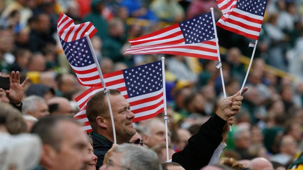 Fans wave flags during the national anthem before an NFL football game between the Green Bay Packers and the New Orleans Saints on Sunday, Oct. 22, 2017, in Green Bay, Wis.