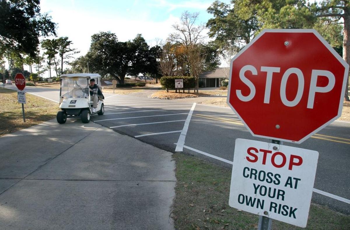 A golf cart crosses Golf Club Drive, leaving the Cardinal golf course at Diamondhead.