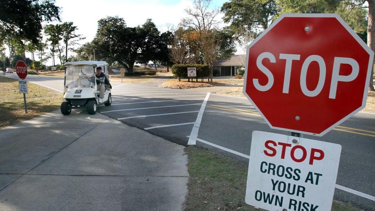 A golf cart crosses Golf Club Drive, leaving the Cardinal golf course at Diamondhead. 