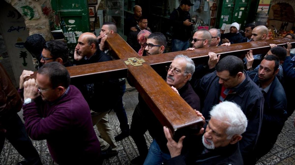 Christian worshippers hold a cross as they walk along the Via Dolorosa towards the Church of the Holy Sepulchre, traditionally believed by many to be the site of the crucifixion of Jesus Christ, during the Good Friday procession in Jerusalem's Old City.