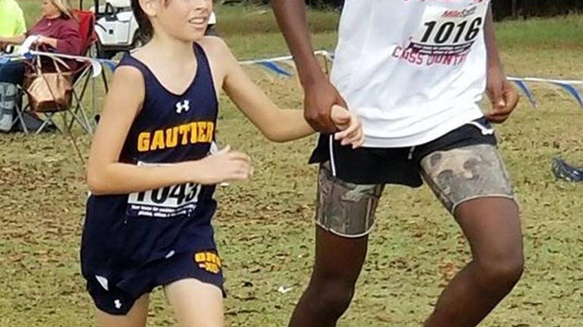 During a cross county race, Joshua Dixon of Forest Hill High School in Jackson (left) helps Liam Jordan of Gautier High School (left) after Jordan pulled a muscle.
