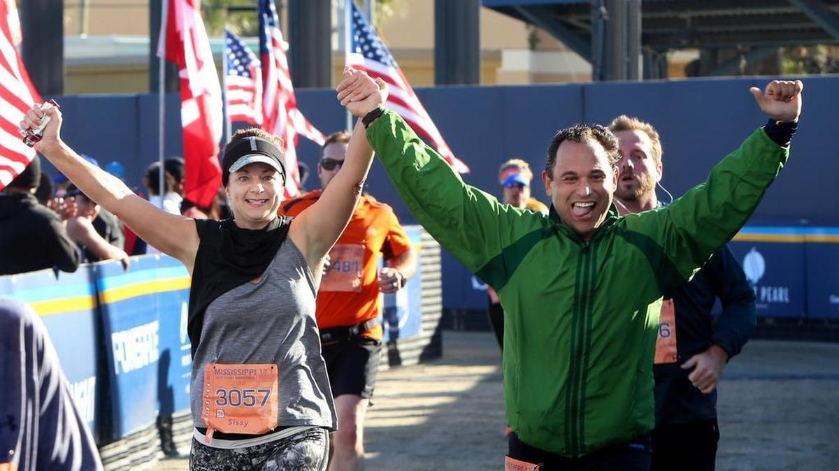 Sissy Moreland and Marcos Rodrigues cross the finish line together at the Mississippi Gulf Coast Marathon, Sunday, Dec. 11, 2016.