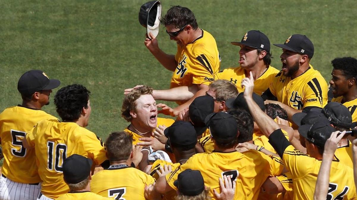 The Southern Miss team mobs Taylor Braley as he crosses home plate after hitting a two-run home run for a come-from-behind victory over Charlotte during USM - Charlotte game at C-USA tournament, Saturday, May 27, 2017.