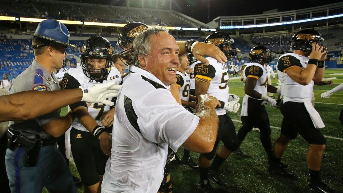 After being doused, Southern Miss head coach Jay Hopson, center, celebrates with his team after defeating Kentucky in an NCAA college football game Saturday in Lexington, Ky.