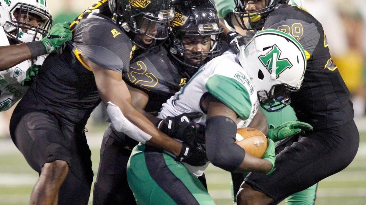 Darian Yancey and a host of Southern Miss defenders bring down Marshall running back Keion Davis Saturday at M. M. Roberts Stadium in Hattiesburg.