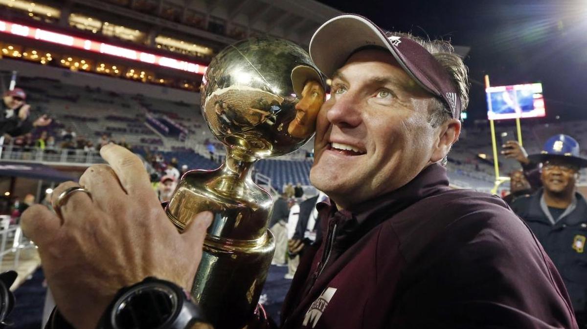 Mississippi State head coach Dan Mullen cuddles up with the "Golden Trophy" awarded the team that wins the "Egg Bowl" rivalry NCAA college football game against Ole Miss in Oxford. Mississippi State won 55-20.