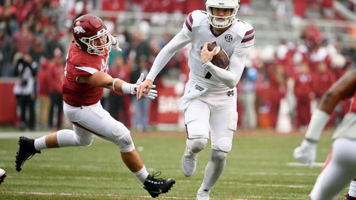 Mississippi State quarterback Nick Fitzgerald slips past Arkansas defender Grant Morgan to score a touchdown.