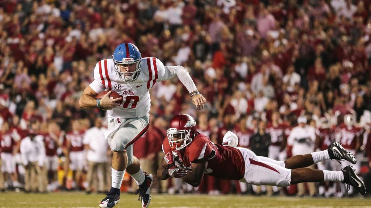 Ole Miss quarterback Chad Kelly (10) outruns a tackle attempt by Arkansas' defensive back Josh Liddell (28).