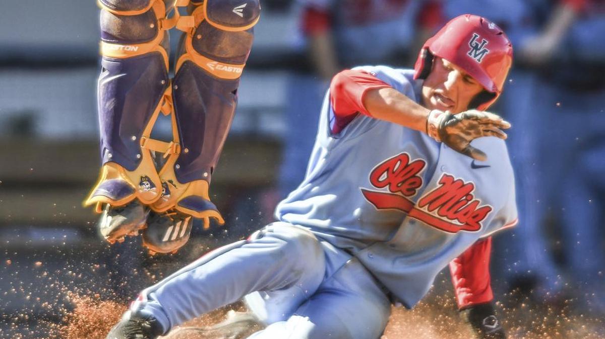 Ole Miss infielder Grae Kessinger, right, scores as East Carolina catcher Travis Watkins jumps for a high throw.