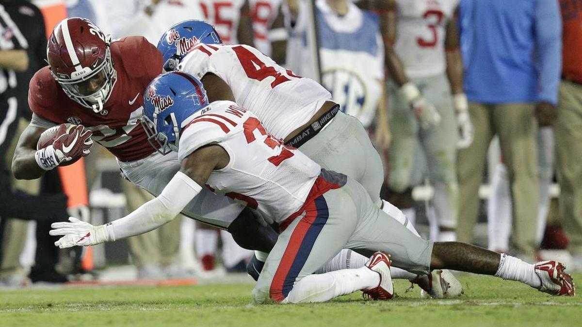 Alabama running back Brian Robinson Jr. is tackled by Ole Miss players during the second half Saturday in Tuscaloosa, Ala.