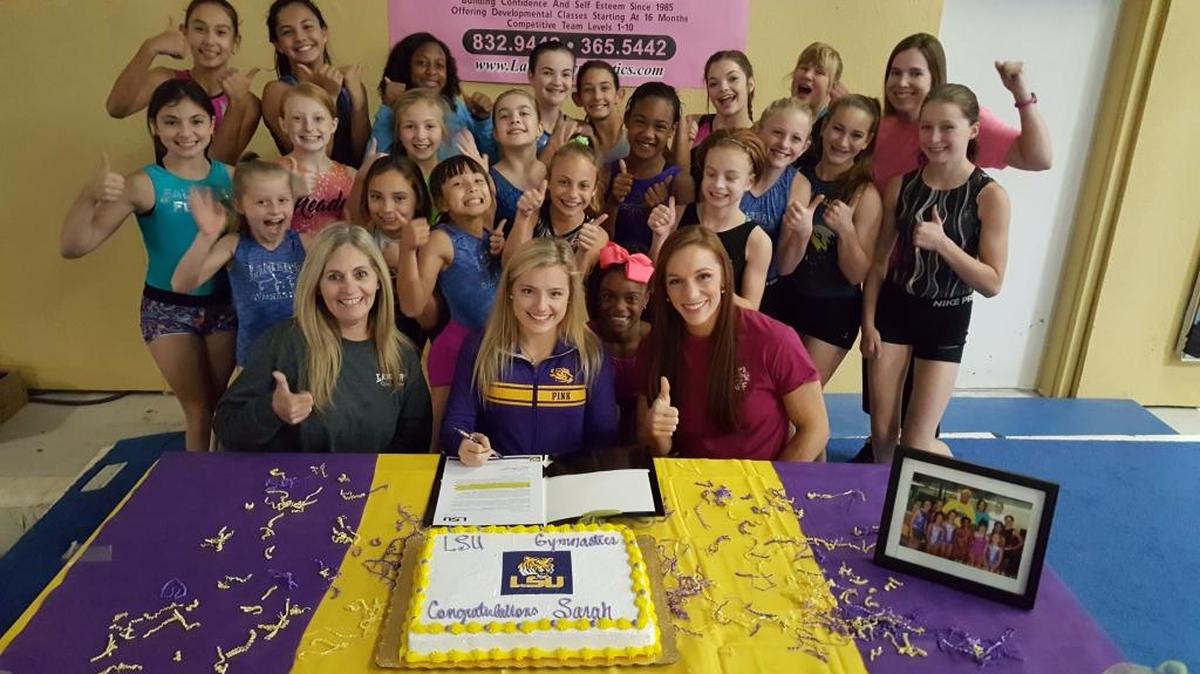 Sarah Edwards (center) is flanked by her coaches, Cindy Lanier Wallace (left), Amanda Zeigler (right) and a cast of young gymnasts at Lanier's Gymnastics in Gulfport, as she signs her Letter of Intent to compete for the LSU women's gymnastics team.
