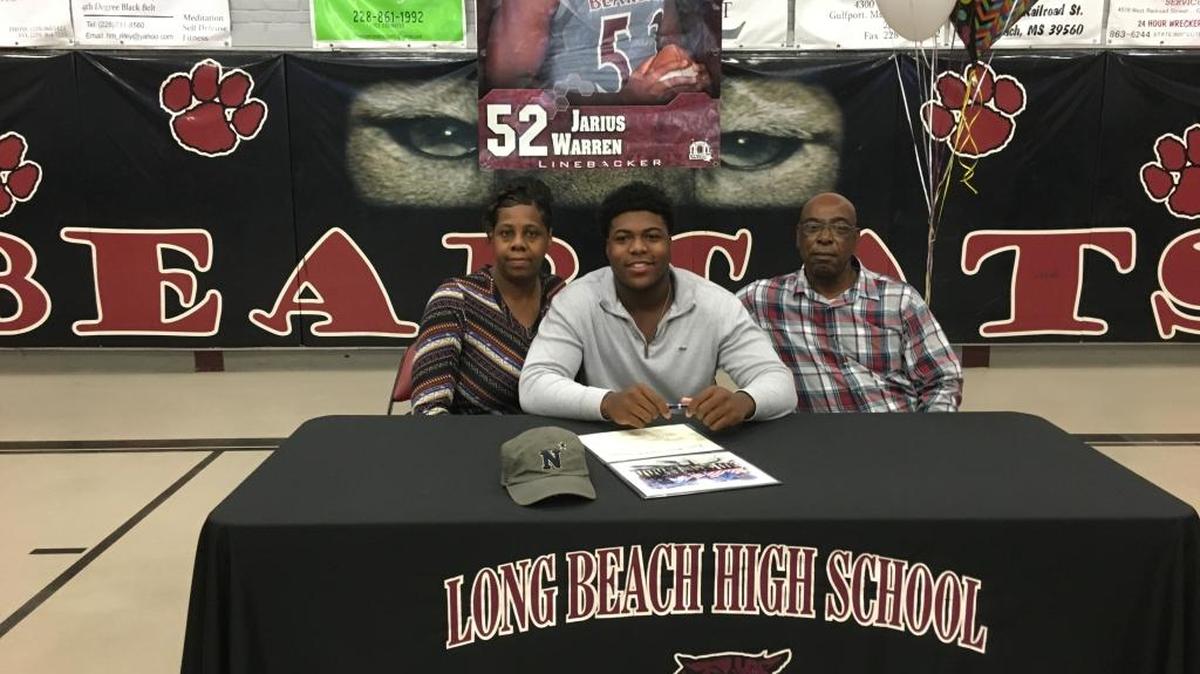 Jarius Warren of Long Beach signs with Navy. He is flanked by his parents Vertilla and Bernard Rogers.