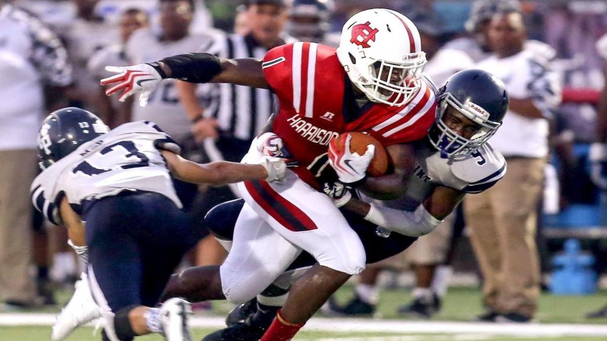 Harrison Central's Keon Moore is tackled by Moss Point's Kobie Ruffin, left, and Anthony Kirkland as he runs the ball Friday, September 2, 2016, in Harrison County.