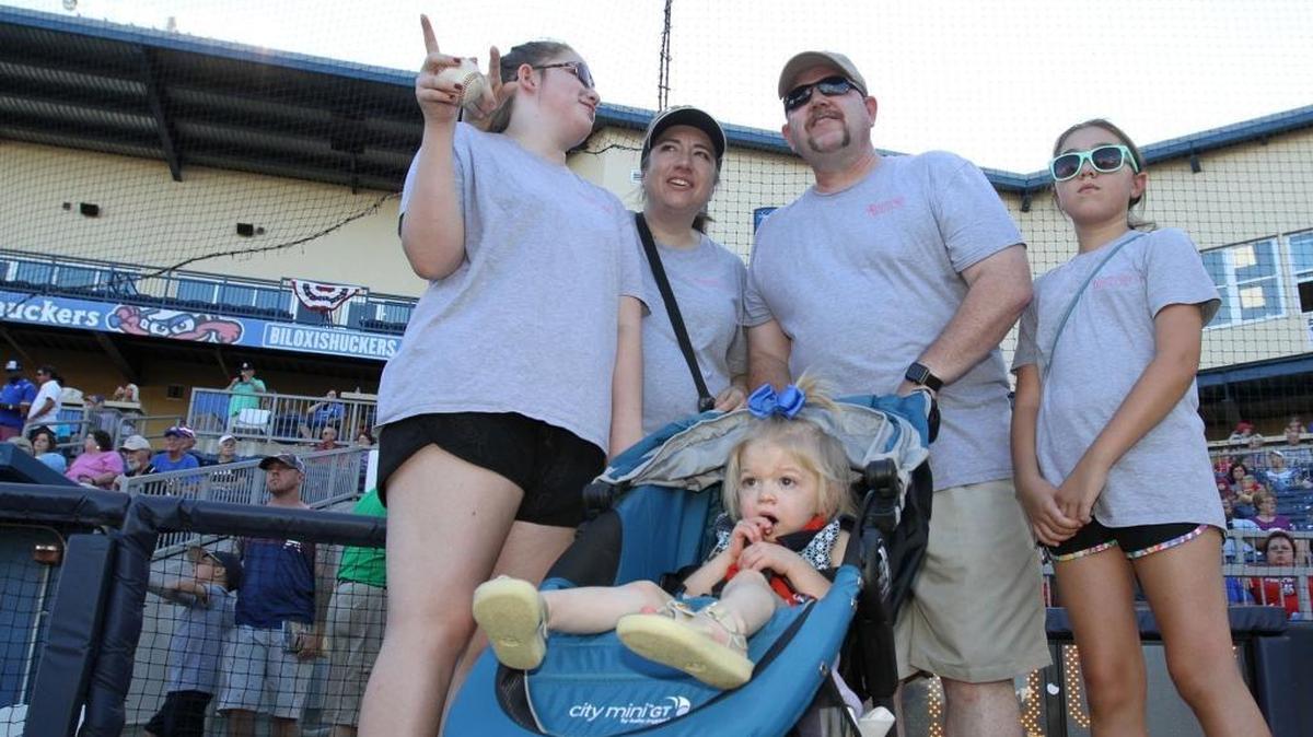 Kylee Cannan of Ocean Springs, left, talks to her parents, Amber Olsen and Tom Cannan, and sister, Jenna, before throwing out the first pitch in honor of her sister, Willow, in stroller, before the Biloxi Shuckers' game at MGM Park in Biloxi on Tuesday.