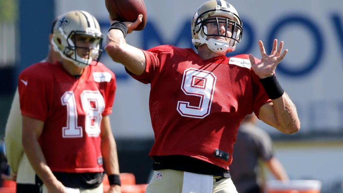 New Orleans Saints quarterback Drew Brees (9) throws a football as Saints quarterback Garrett Grayson (18) watches during football training camp, in Foxborough, Mass.