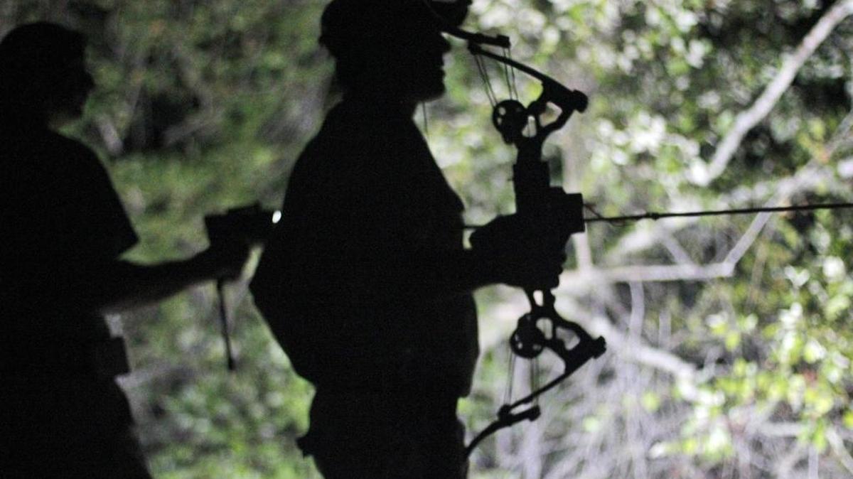 Trey Nichols of Richland stands with his bow at the ready as Shannon Cutts of Bolivar County uses a spotlight to pan the surface of the Pascagoula River for any signs of an alligator the night of Sept. 3, 2015.