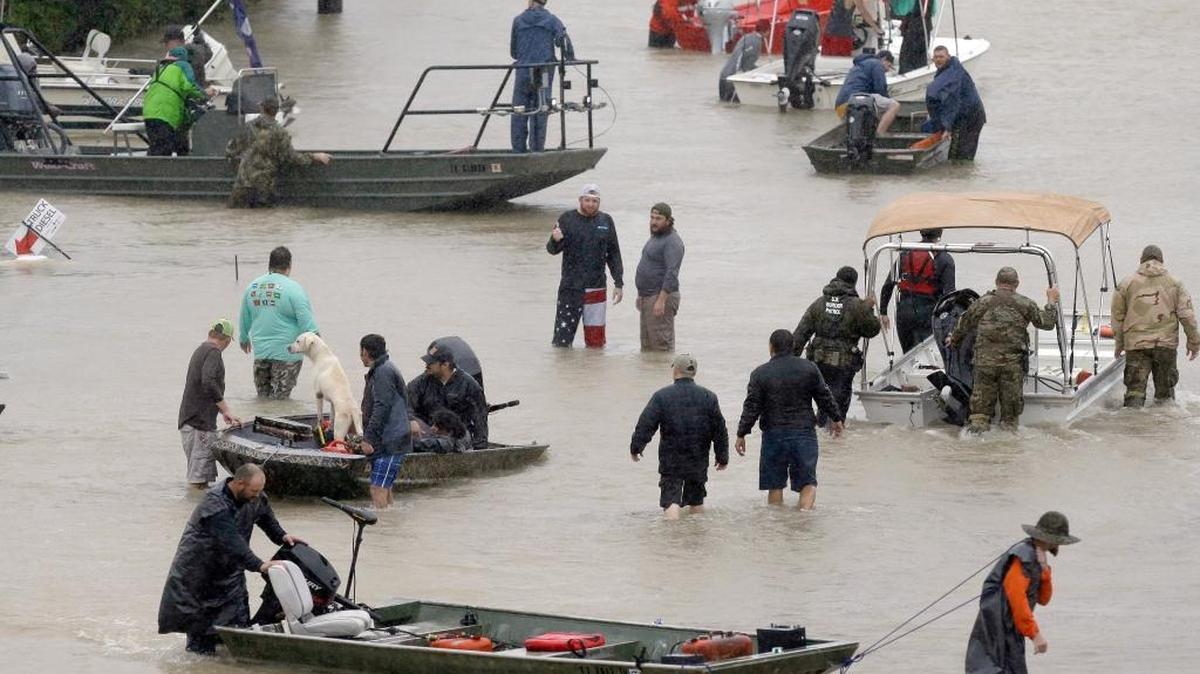 People and rescue boats line a street at the east Sam Houston Tollway as evacuations continue from flooding in Houston, Texas, Monday, Aug. 28, 2017, following Tropical Storm Harvey. Floodwaters reached the rooflines of single-story homes Monday and people could be heard pleading for help from inside as Harvey poured rain on the Houston area for a fourth consecutive day after a chaotic weekend of rising water and rescues.
