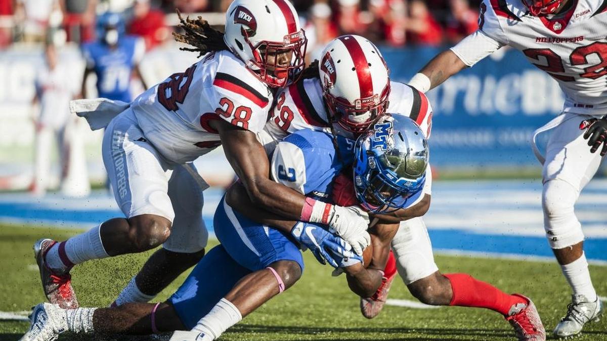 Western Kentucky defensive backs Drell Greene (28) and Leverick Johnson (29) tackle Middle Tennessee wide receiver Richie James (3) during WKU's 44-43 double overtime winon Oct. 15 in Murfreesboro, Tenn.