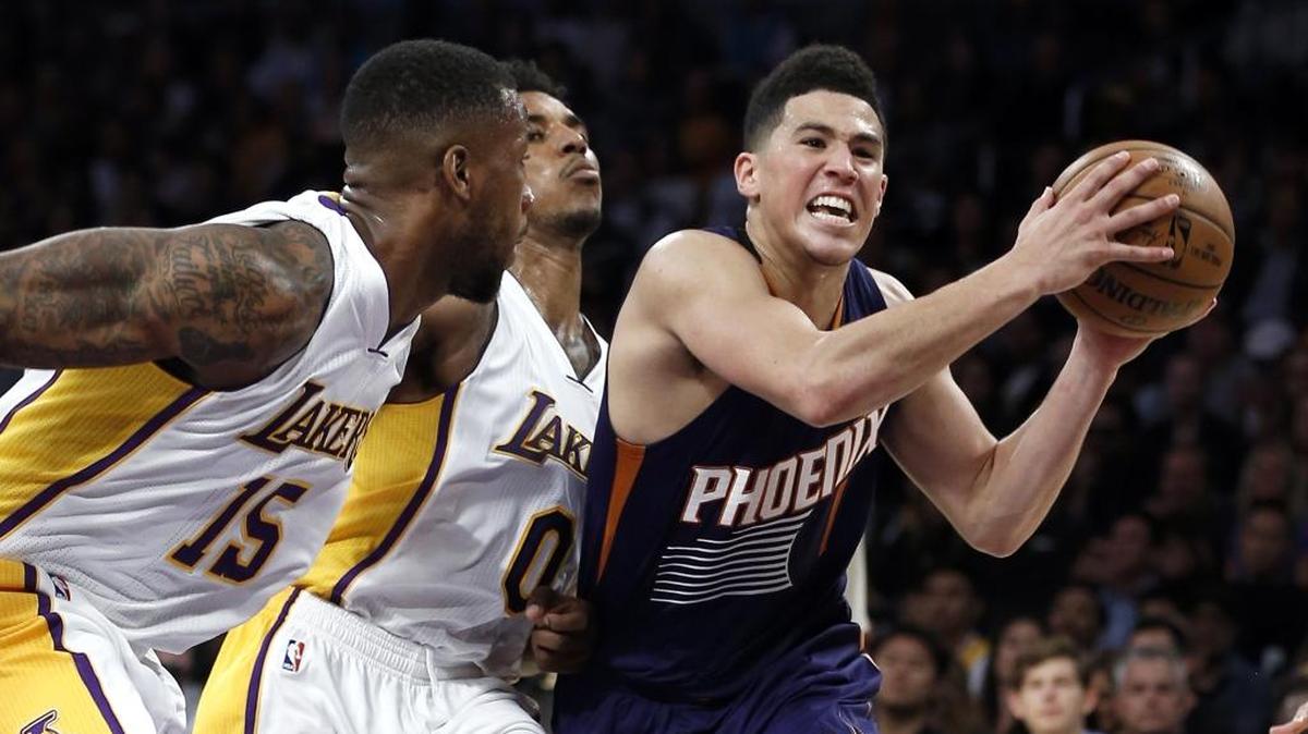 Los Angeles Lakers forward Thomas Robinson, left, and guard Nick Young, center, chase after Phoenix Suns guard Devin Booker, right, Sunday in Los Angeles. The Lakers won 119-108.